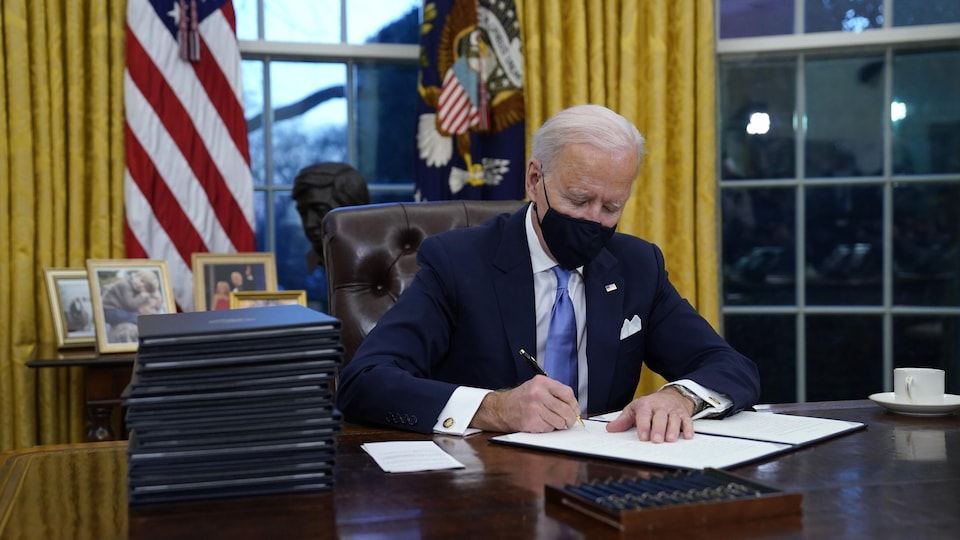 Joe Biden signe un décret avec une plume. 