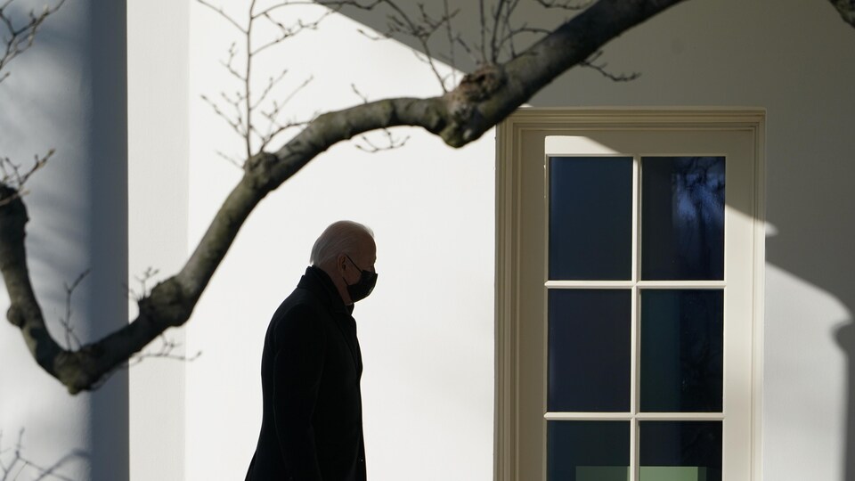 Le président des États-Unis, Joe Biden, marche vers le bureau ovale dans un éclairage à contre-jour.