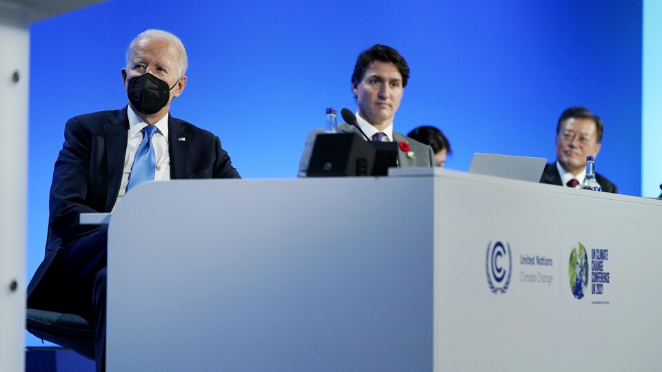 Joe Biden, Justin Trudeau et Moon Jae-in sont assis côte à côte derrière un bureau.