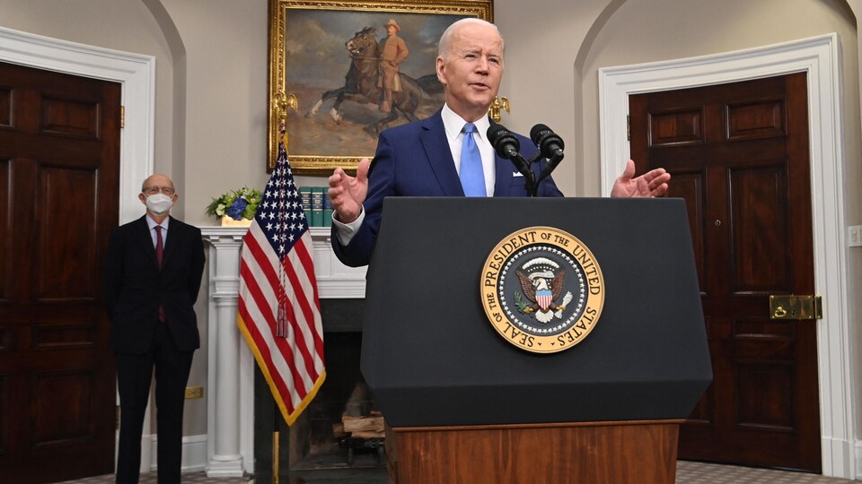Joe Biden devant un lutrin, à la Maison-Blanche. En retrait, le juge Stephen Breyer, masqué.