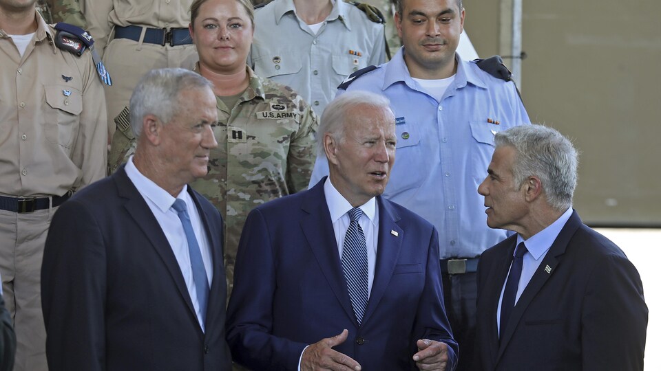 Benny Gantz, Joe Biden et Yaïr Lapid discutent devant des militaires en uniforme.