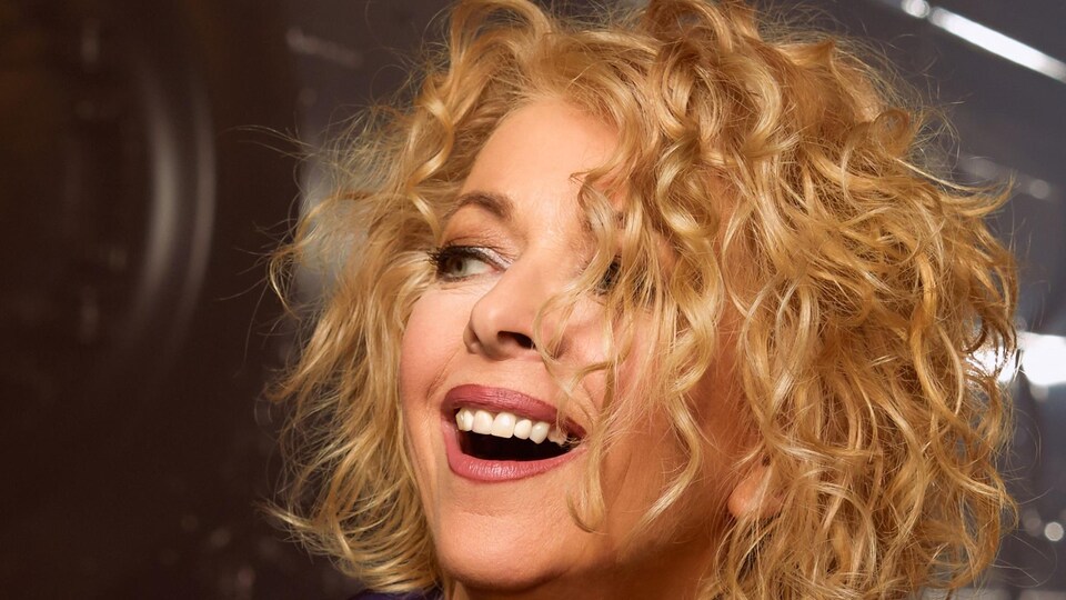 Une femme regarde vers sa droite en souriant.