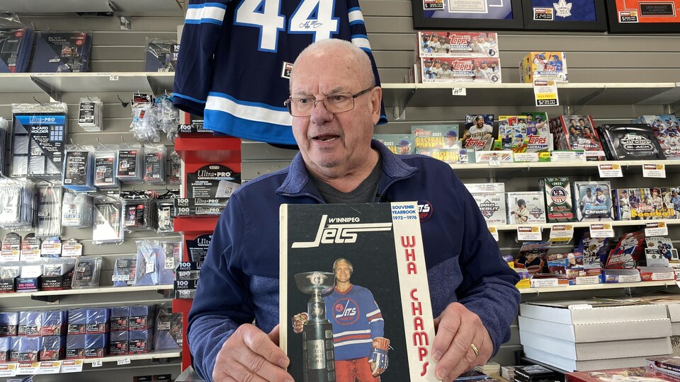 Joe Daley photographié dans son commerce de Winnipeg tenant un livre avec Bobby Hull sur la couverture, le 30 janvier 2023. 