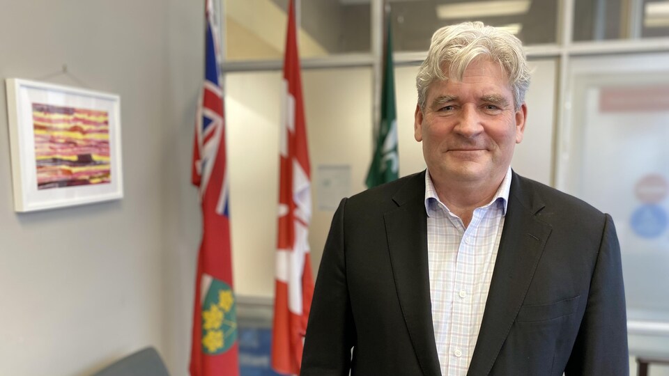 Ontario Liberal MLA John Fraser in his office in front of the flags.