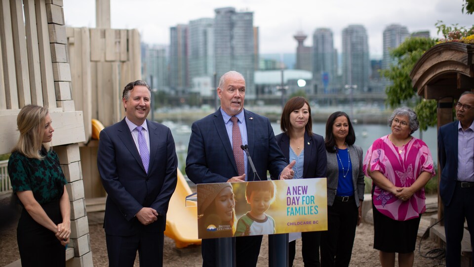Le premier ministre de la Colombie-Britannique entouré du maire de Vancouver et de la ministre d'État pour la Petite enfance lors d'une annonce à Vancouver, le 4 juillet 2019.