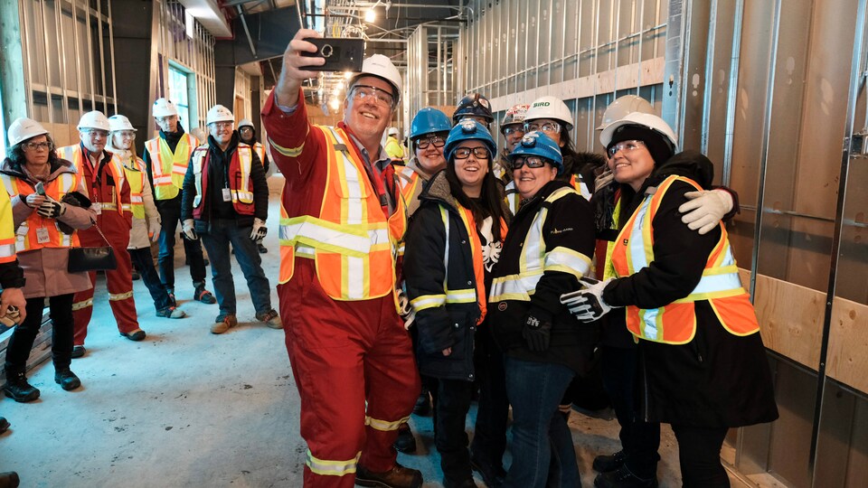 John Horgan se prend en photo avec huit ouvriers portant des casques dans une usine de LNG Canada.