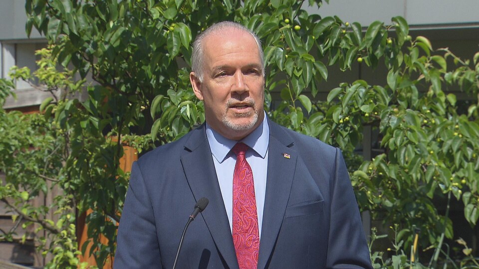 John Horgan debout devant un arbre.