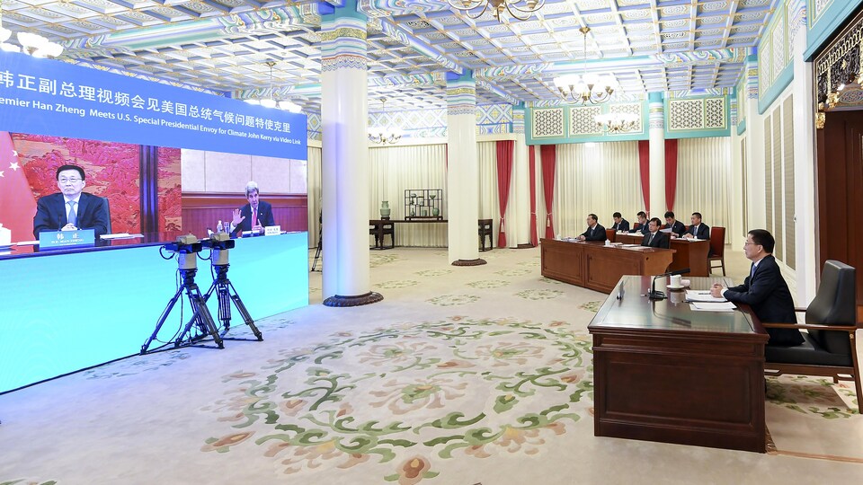 Une vidéoconférence réunit plusieurs personnes sur grand écran dans une salle.