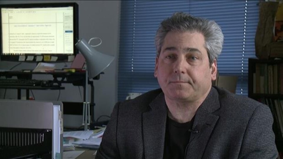 M. Lawford est assis à son bureau et s'adresse à la caméra.
