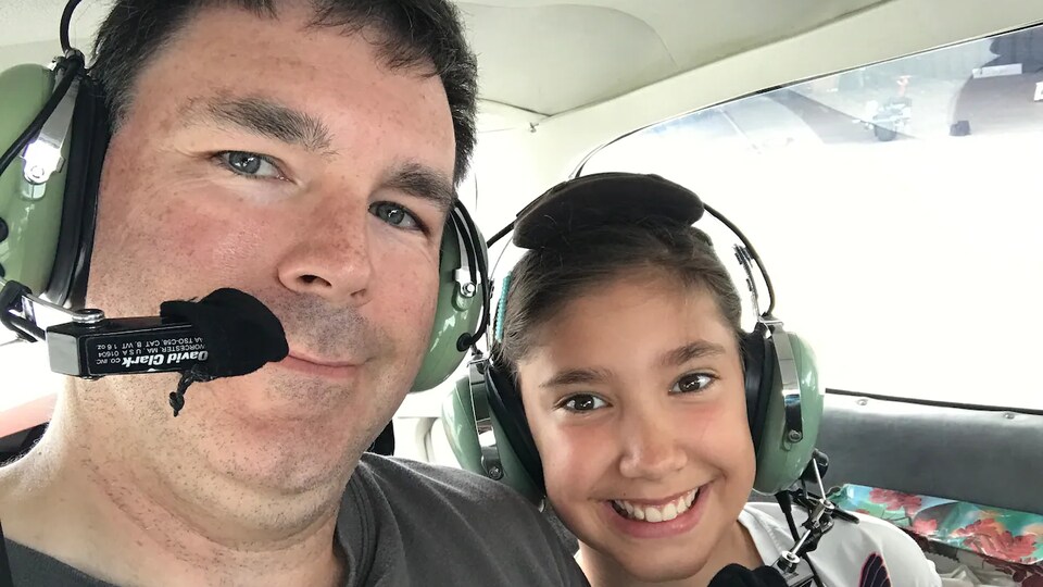 John Phillips avec sa fille dans un hélicoptère avec un casque d'écoute.