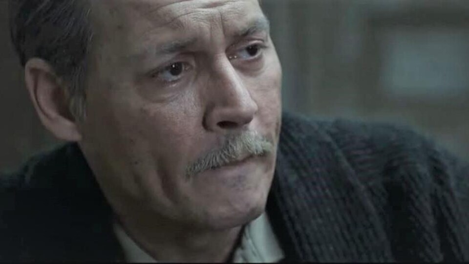 Johnny Depp porte une moustache et des cheveux grisonnants et affiche un air inquiet.