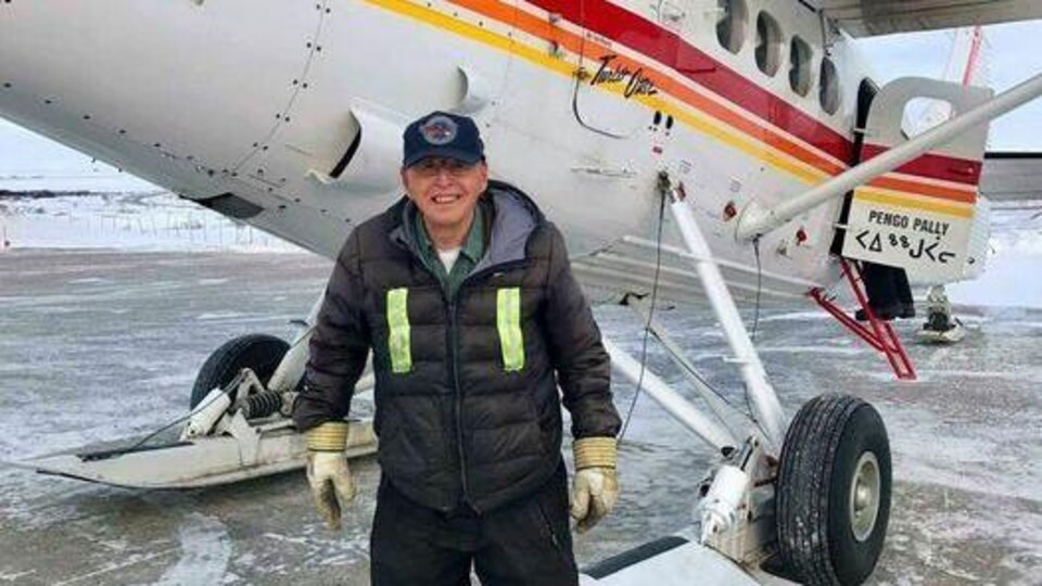Johnny May pose devant un avion.
