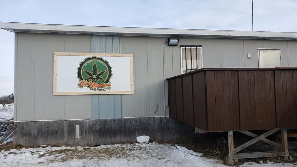 Un bâtiment rectangulaire sur lequel une pancarte montre une feuille de marijuana et le nom de l'entreprise Joint Adventures