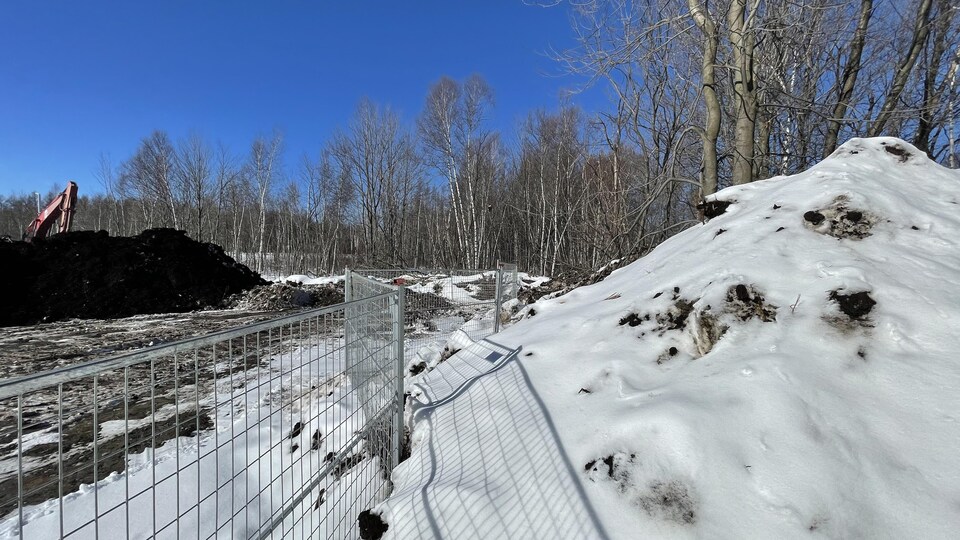 Une clôture dans la neige bordée d'un chantier de construction.  