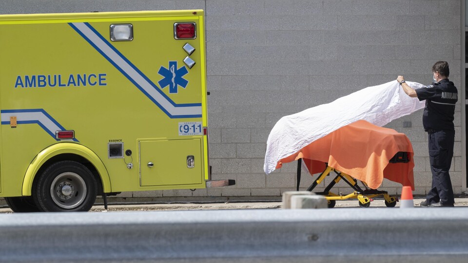 Un ambulancier dépose un drap blanc sur une civière.