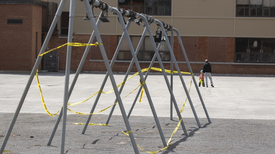 Une banderole entoure les installations pour balançoires dans une cour d'école.