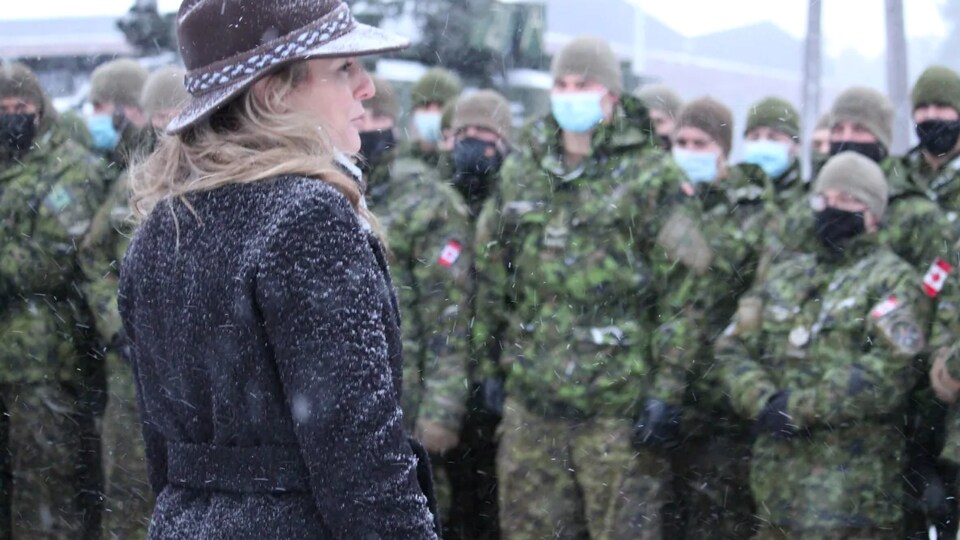 Mélanie Joly se tient devant des soldats en hiver. 