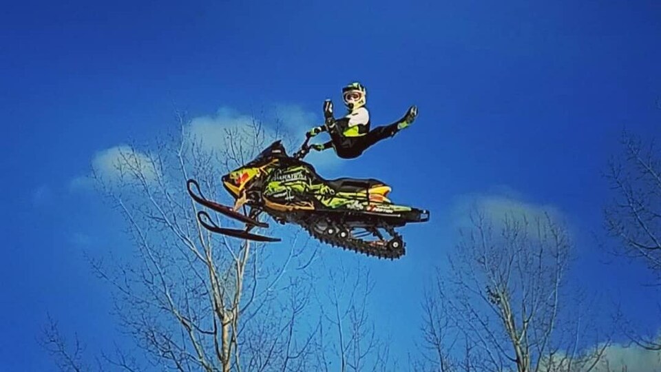 Un homme fait une acrobatie lors d'un saut à motoneige.