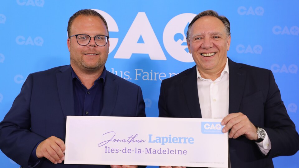Jonathan Lapierre et François Legault tiennent une pancarte.