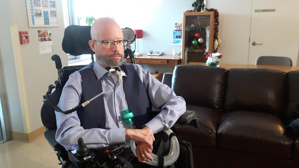 Jonathan Marchand assis dans son fauteuil roulant électrique avec son respirateur artificiel