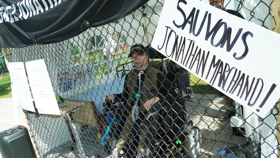 Jonathan Marchand manifeste, dans sa cage, devant l'Assemblée nationale.