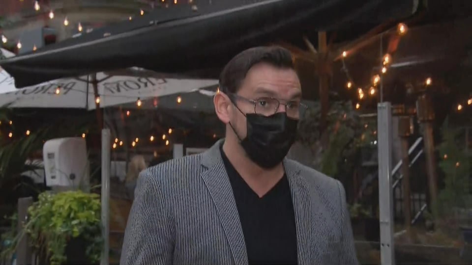 Il porte un masque et regarde la journaliste.