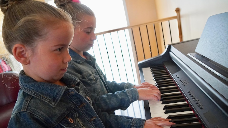 Deux jeunes filles jouent du piano.