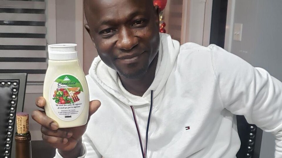Joseph Dongo montre une bouteille de sa vinaigrette.