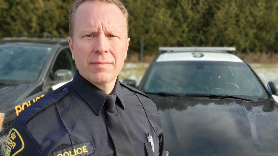 Joshua Cunningham pose devant une voiture de la Police provincial de l'Ontario.