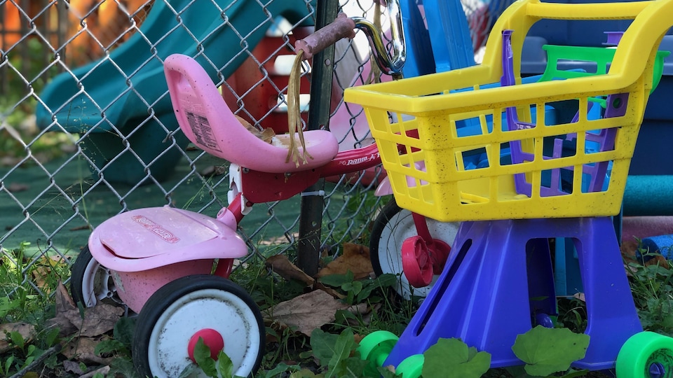 Un tricycle rose et un carrosse en plastique dans la cours de la garderie où se sont produits les événements.