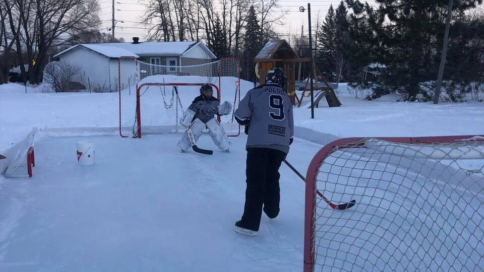Deux jeunes filles jouent au hockey dans leur cour arrière.