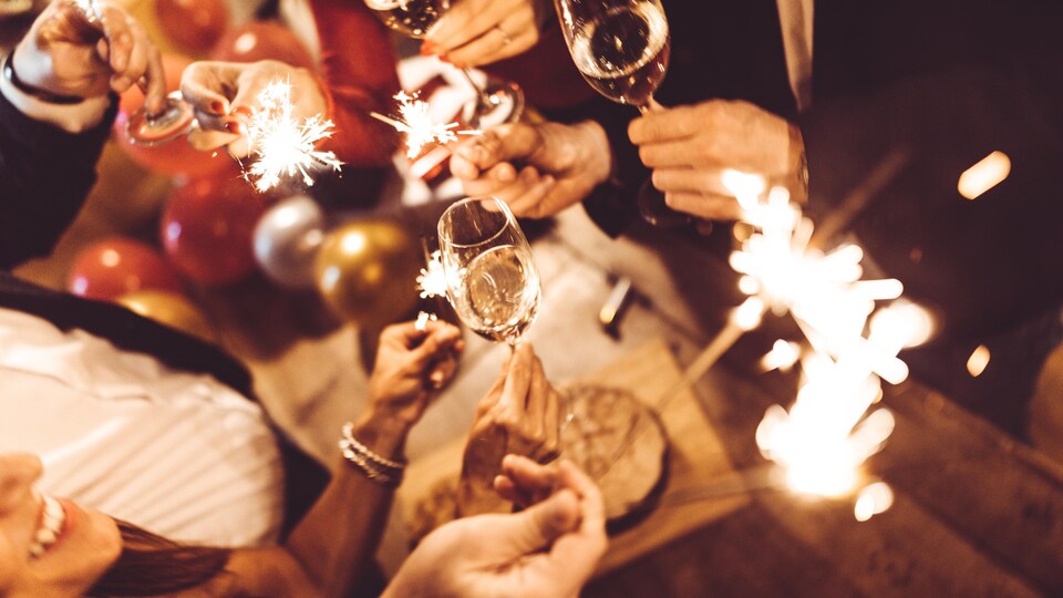 Des gens célèbrent le jour de l'An avec des feux de bengale et des coupes de champagne.