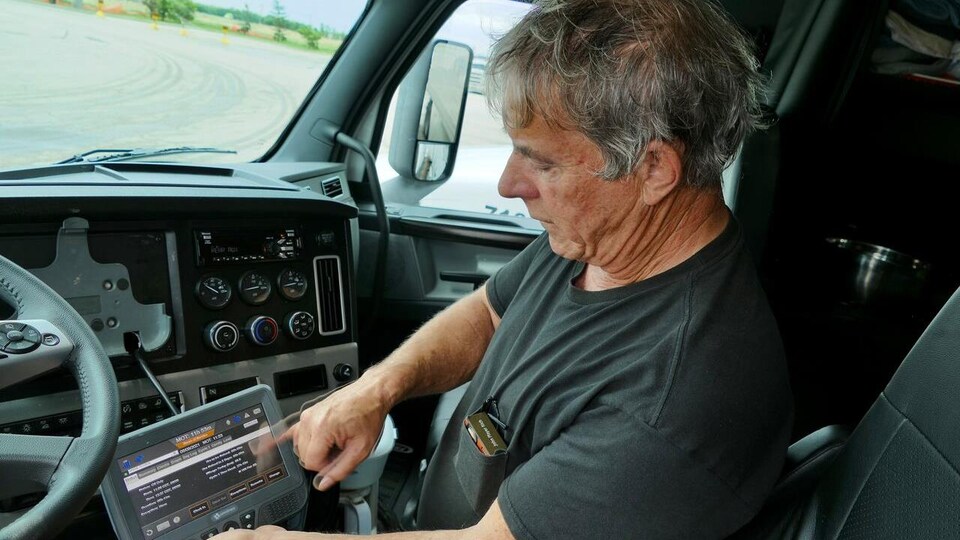 Un homme utilise un carnet de bord électronique à bord de son camion.