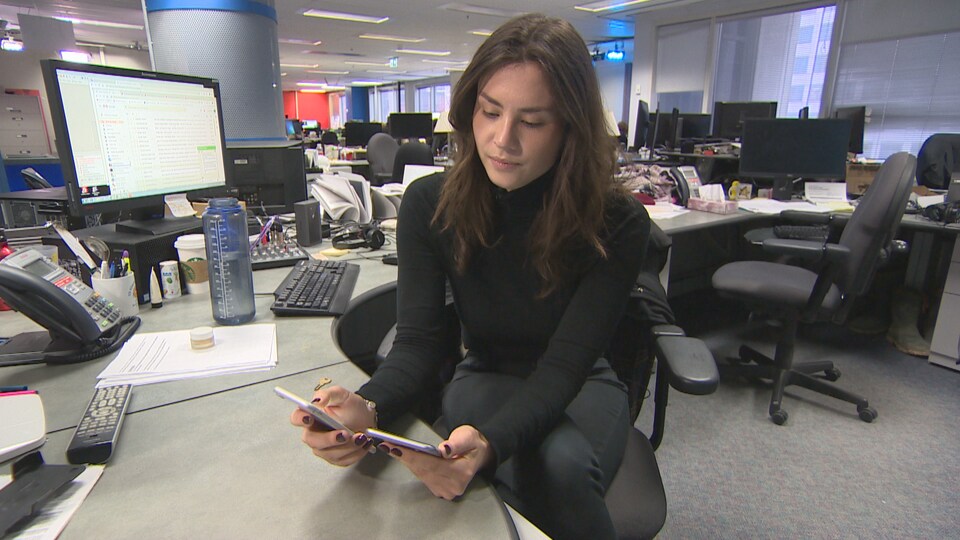 La journaliste Charlotte Mondoux-Fournier consulte ses téléphones intelligents.