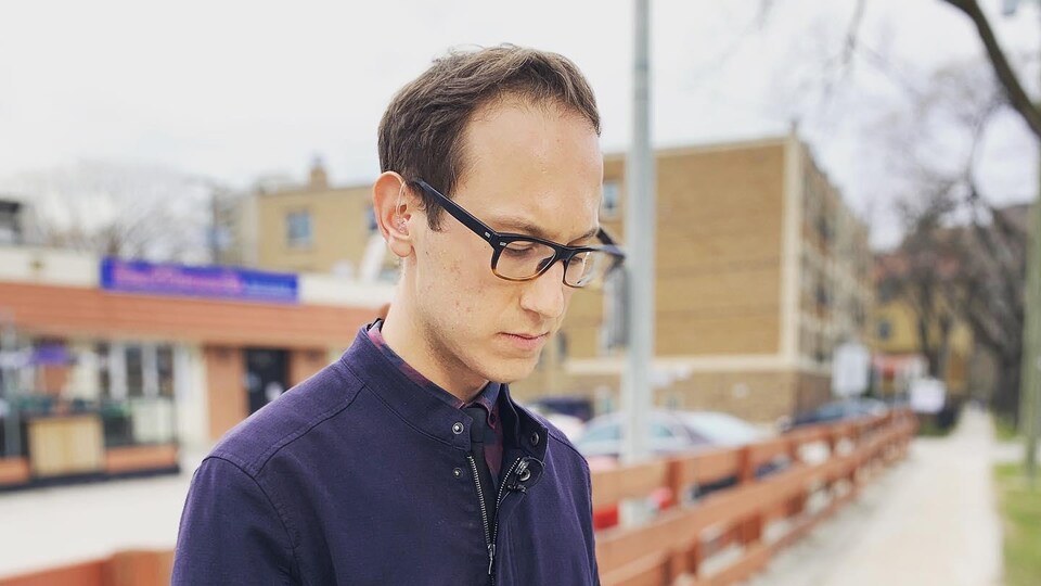 Patrick Foucault dans une rue, avec son téléphone cellulaire.