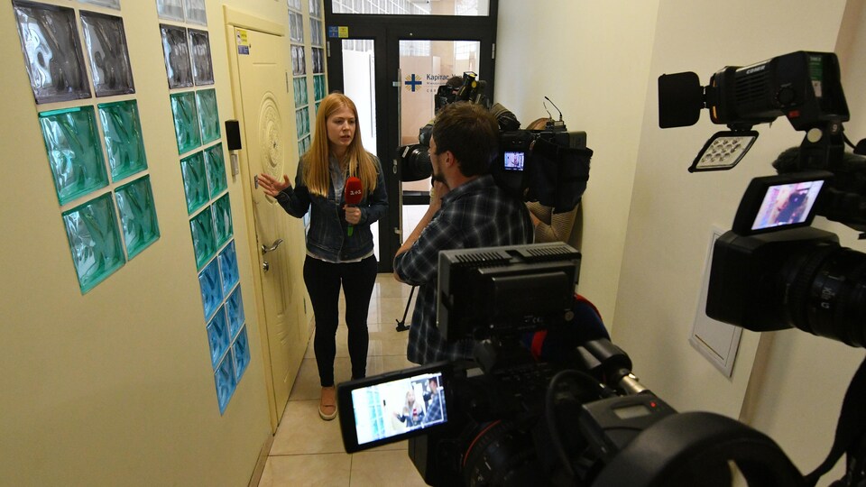 Journalistes et caméramans attendent dans un couloir.