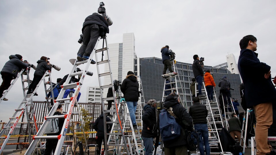 Des photographes et caméramans sont juchés sur des échelles en attendant la sortie de Carlos Ghosn de la prison de Tokyo.