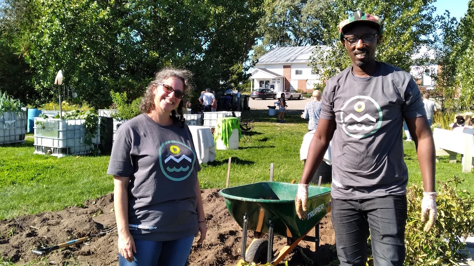 Deux personnes portant un t-shirt sur lequel est imprimé le logo de la MRC de Témiscamingue sourient dans un jardin.