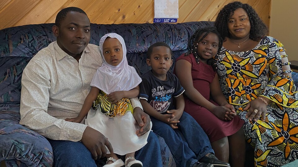 Des parents et leurs trois enfants assis sur un divan.