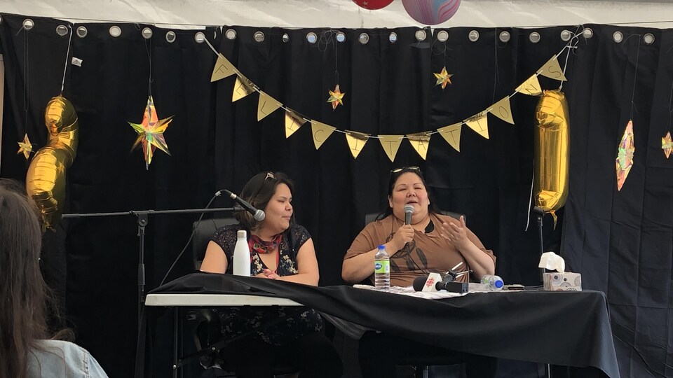 Joyce Grégoire et Nicole Wapistan sont installées à une table décorée de façon festive.