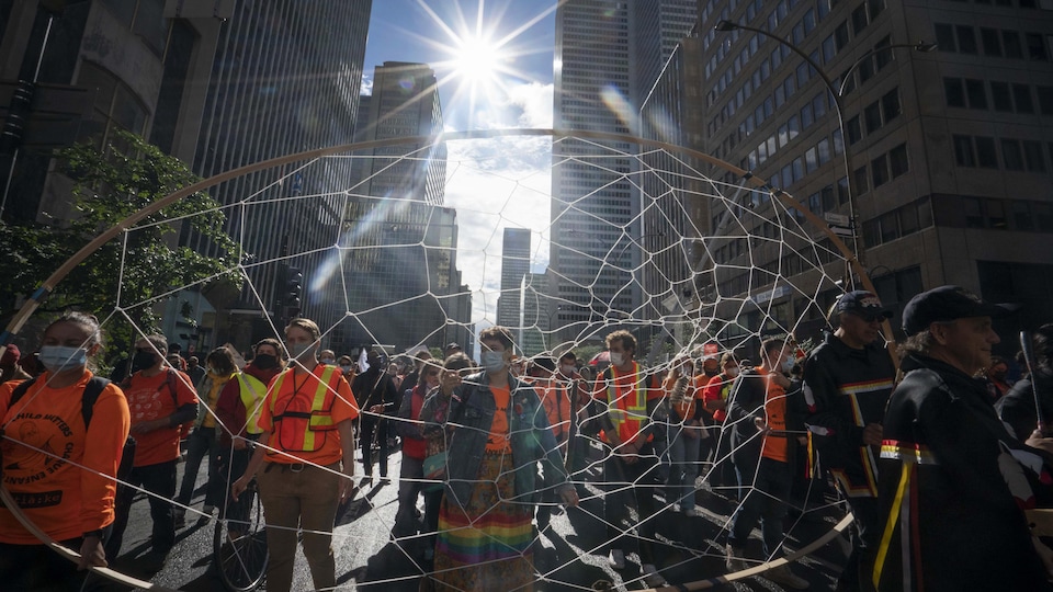 Une foule dans la rue et certains portent un attrape-rêve géant.