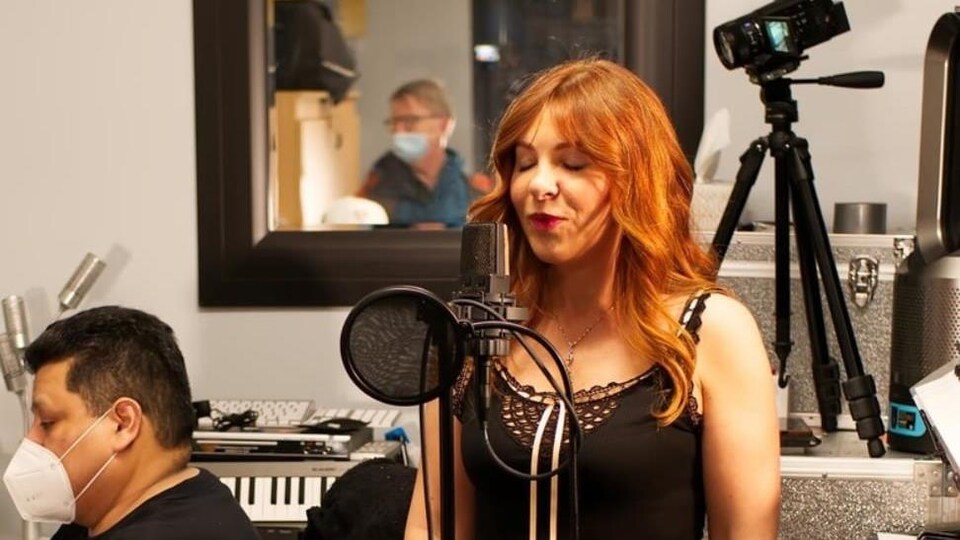 Joy Chapan chante dans un studio d'enregistrement.