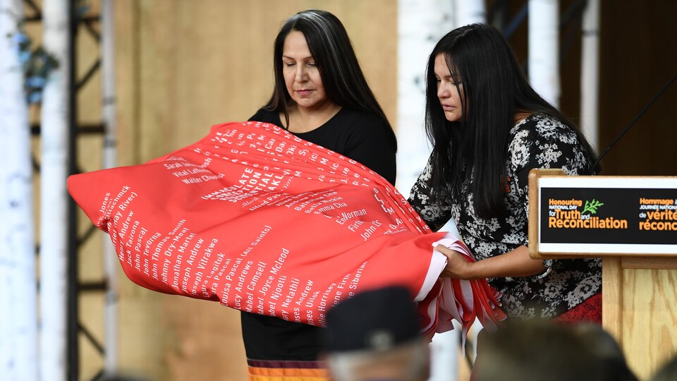 Joyce Hunter et Stephanie Scott déposent un tissu cérémoniel portant les noms de 2 800 enfants morts dans les pensionnats autochtones.