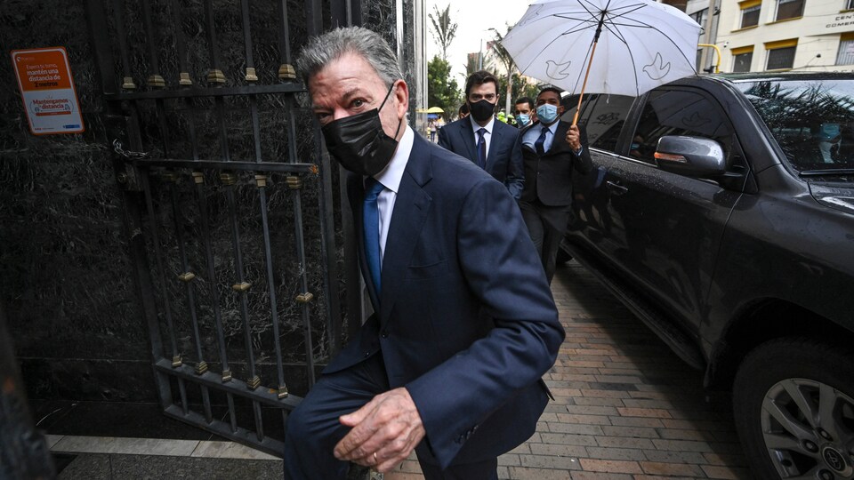 L'ancien président Juan Manuel Santos portant un masque et entrant dans un édifice.