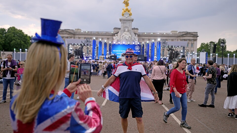 Un homme est photographié devant la scène du palais de Buckingham.