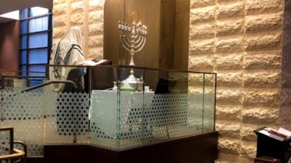 On voit un rabbin prier devant une ménorah dans une synagogue de Toronto.