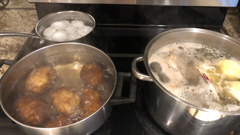 Des oeufs et des patates sont en train de bouillir sur une cuisinière.