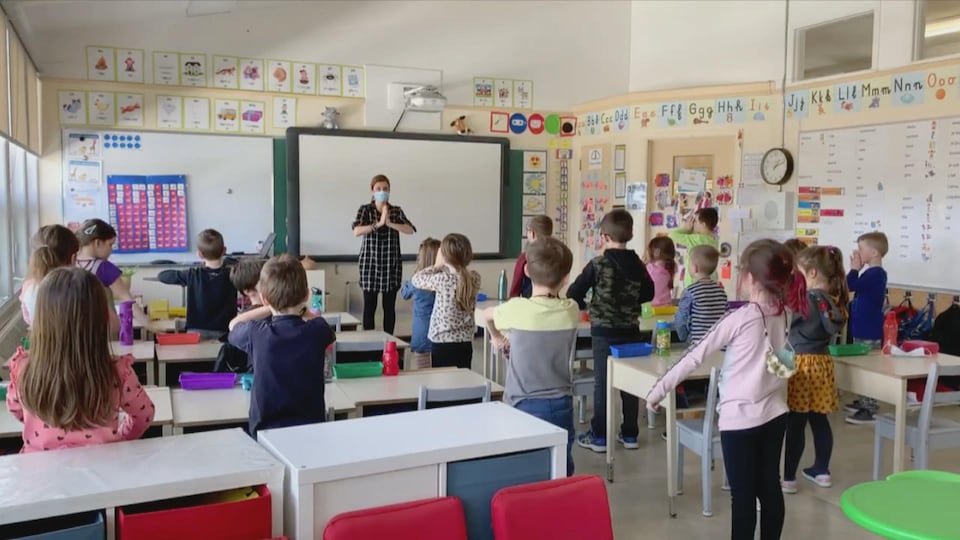 Judith Goulet fait un mouvement de yoga devant sa classe. Les élèves l'imitent.