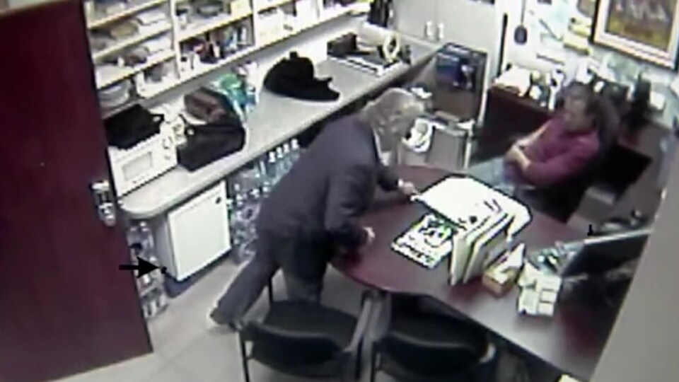 Une capture d’écran de la vidéo montre Michel Girouard alors avocat avec un de ses clients, un trafiquant de drogue. Elle permet de voir l’avocat qui glisse une liasse de billets sous un sous-main en échange de ce qui semble être un papier roulé.
