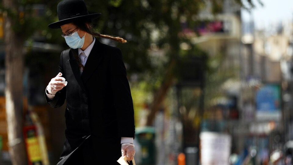  L'homme, qui porte un masque et des gants, traverse la rue